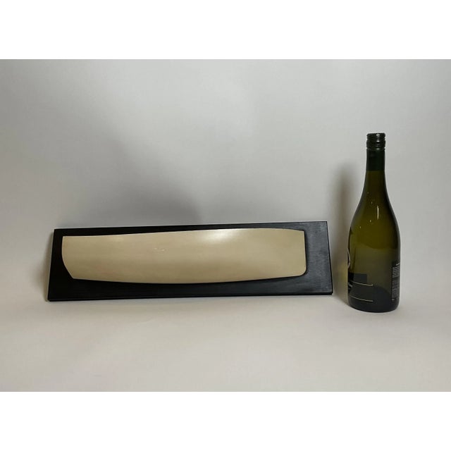 Carved half model of a catboat sloop. Hull is painted white and is mounted to a painted backboard. The name "Cook" is...