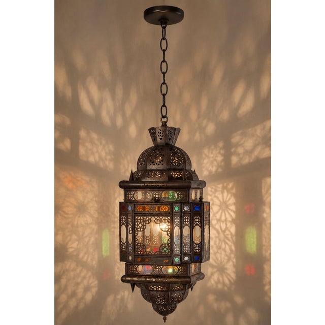 A striking vintage Moroccan hanging lantern, handcrafted in Marrakech from pierced metal with a rich dark bronze patina...