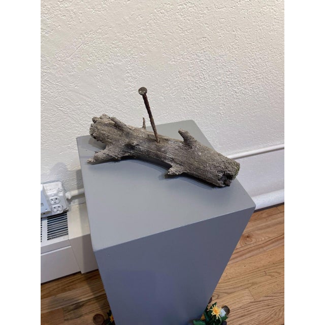 This mixed media piece presents a weathered piece of wood, punctuated by a lone rusty nail, evoking themes of decay and...