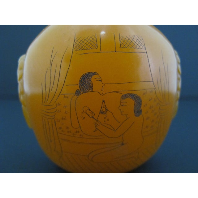 Chinese snuff bottle crafted from an orange-yellow resin material with finely incised and painted pictures depicting...