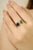 This ring is crafted in 18k white gold, featuring an emerald-cut blue sapphire and a pear-cut emerald, together weighing...