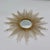 A classic sunburst/starburst wall mirror featuring radiating metal rays in a warm gold-toned finish, centered around a...