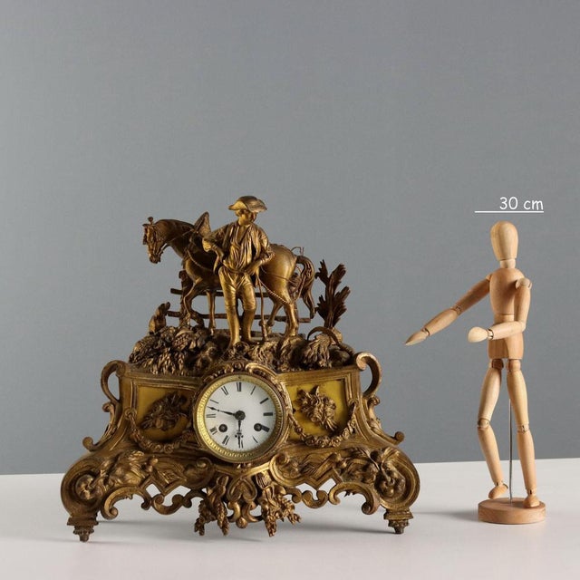 Gilded antimony clock with plant motifs and floral garlands. The clock is surmounted by a farmer with a horse and a dog,...
