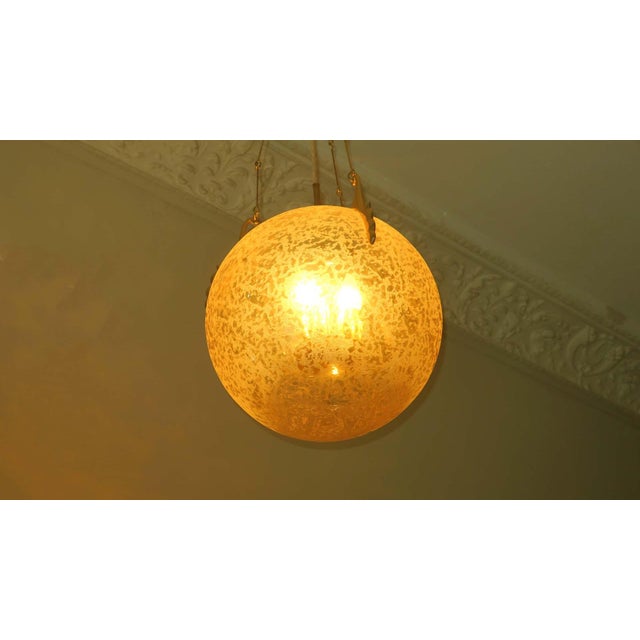 Impressive brass and frosted glass globe pendant from the 1970s from Doria Leuchten. 3 lights hang freely suspended inside...