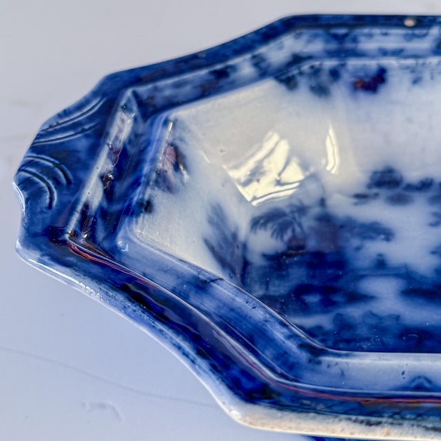 An antique flow blue footed bowl featuring rich cobalt decoration against a creamy white ground. Its elongated octagonal...