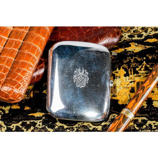 This gleaming Chinese silver export cigarette case by Wang Hing & Co. features an elegant hand-chased armorial coat of...