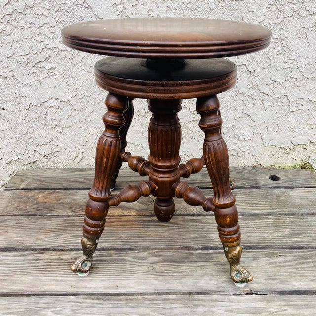 This is an antique piano stool from the early 20th Century. Made from oak, it has an adjustable swivel seat and...