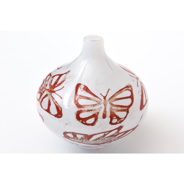 This vintage Swedish Kosta Boda vase or vessel is white cased with red butterflies surround. It is signed and labeled...