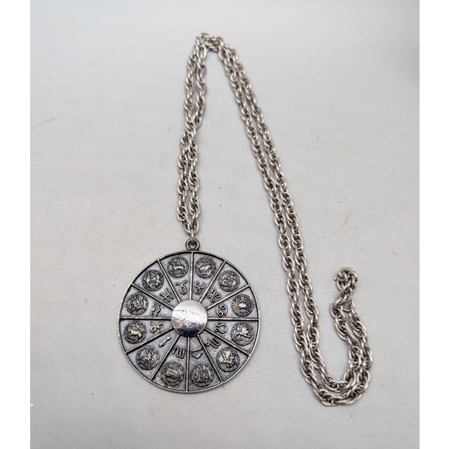 1970s silvertone round engraved horoscope pendant necklace with spring ring clasp. Marked "NAPIER©" on the back. Pendant...
