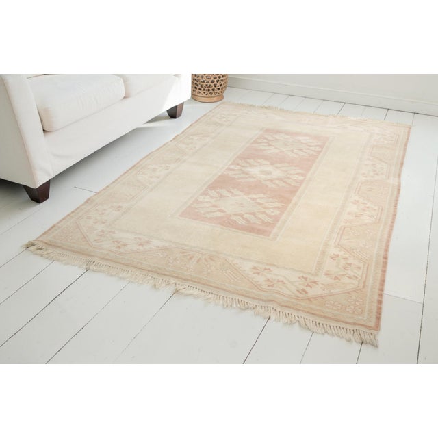 This is a vintage Turkish Oushak rug from the Mid 20th Century. The piece was hand-knotted.