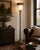An elegant classical torchiere floor lamp featuring a richly detailed fluted column, sculptural weighted base, decorative...