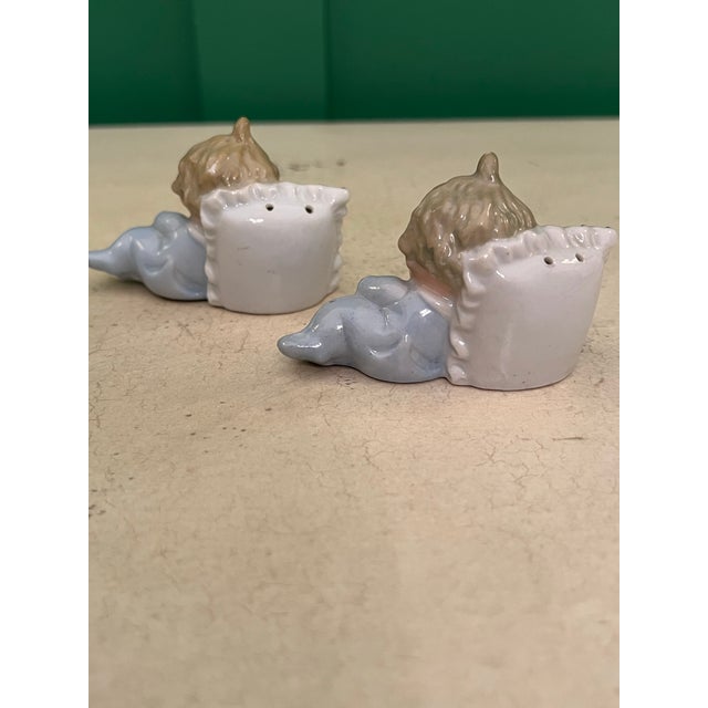 Adorable set of salt and pepper shakers! Two baby boys and their pillows. Soft blue outfits with gilt accents.