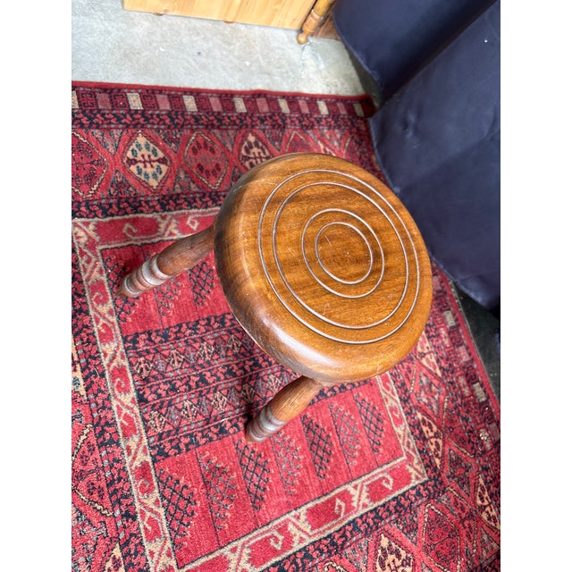 Elegant antique Breton stool in solid wood, resting on three turned legs, with a design that is both understated and...