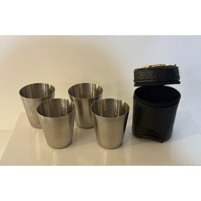 A vintage USSR portable 4-piece nesting vodka shot cup set, presented in its original black zip travel case adorned with...