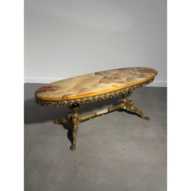 Elegant vintage coffee table featuring a stunning oval onyx top with beautiful natural veining in warm beige, honey and...