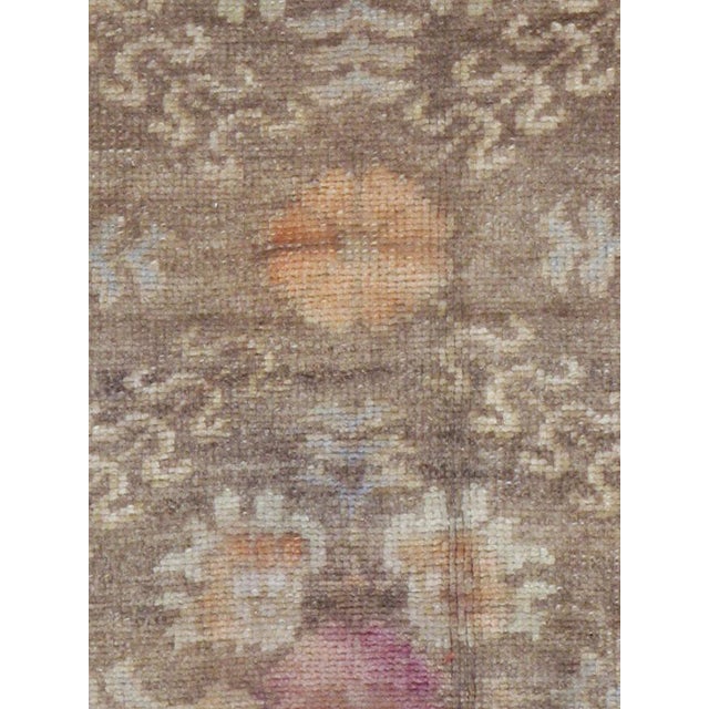 This mid-20th-century Turkish Anatolian accent rug presents an allover floral design arranged across a muted taupe-brown...