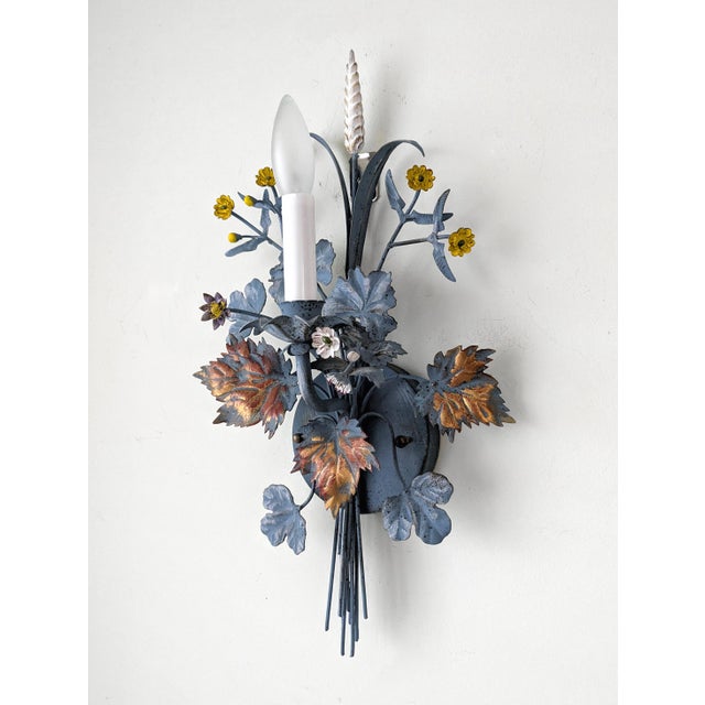 A stunning and rare pair of 1940's Italian tole electric wall sconces. The sconces feature a floral and leaf bouquet...