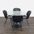 This Room and Board dining set includes a round glass-top table with a sturdy black base and four matching black chairs....
