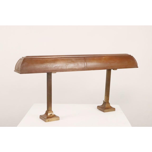 Antique 1910s Industrial style bank desk lamp featuring a long, curved shade designed to direct light downward, supported...