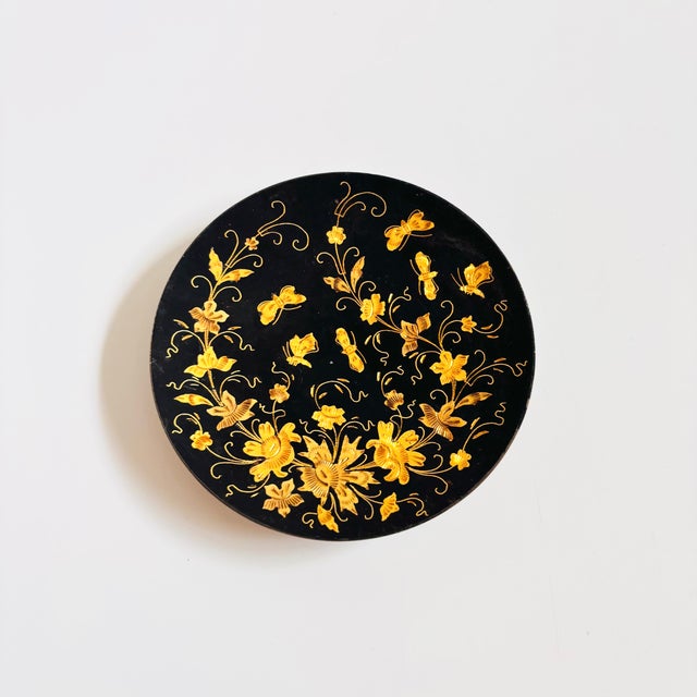 A vintage circular brass tray. Black finish to the tray with a highly detailed etched design of flowers and insects on the...