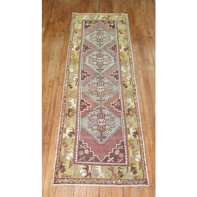 Mid-20th century wool Turkish runner with a geometric design on a purple field. The 4 medallions are gray Measures: 3'x 9'8".