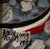 This 1998 oil on canvas of boats on a rocky shore with looming mountains in the background is signed “Yang” in both...