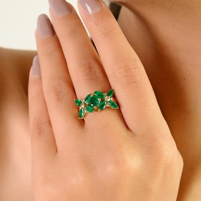 This floral cluster ring featuring 9 marquise & round cut emerald totaling 3 carats, set in 14k yellow gold. The center...