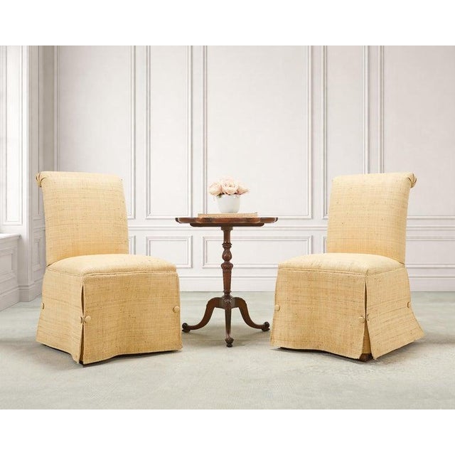 An organic modern pair of scrolled and skirted slipper chairs crafted from woven raffia grasscloth. The chairs feature a...