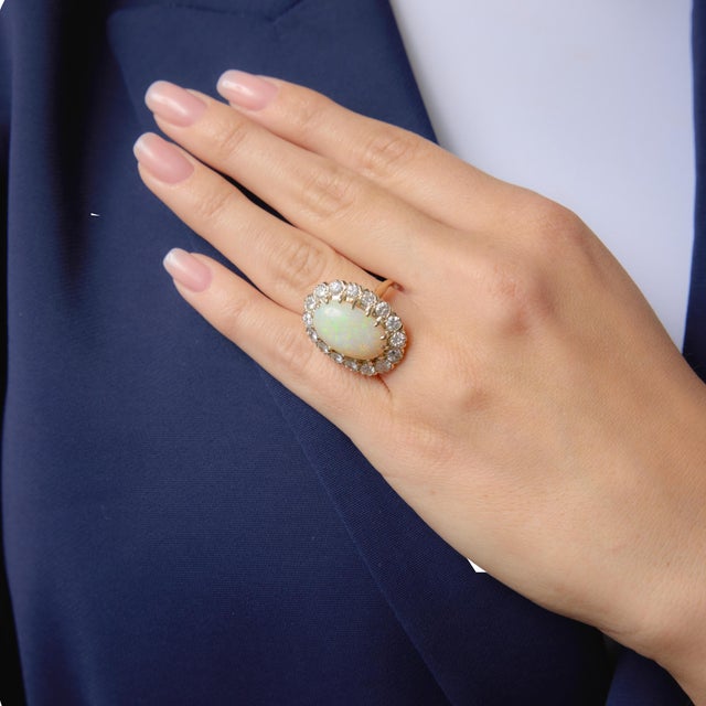 This captivating vintage cluster ring centers on a mesmerizing cabochon cut opal measuring approximately 17.91mm by...