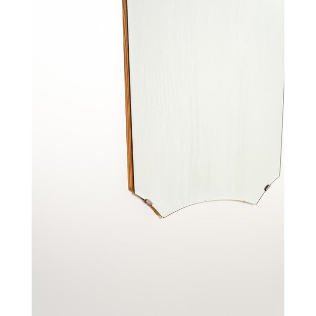 A distinctive shield-shaped wall mirror with a mixtilinear profile defined by concave curves at the top and bottom. The...