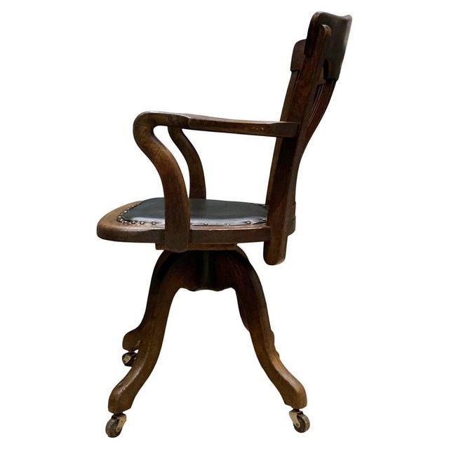 A victorian antique oak curved railback clerks desk chair. with curved swan arms, original black porcelain castors, black...