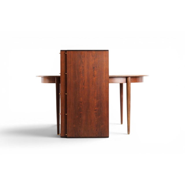 This 1960s Danish oval dining table is crafted from richly figured rosewood, its sweeping oval form anchored by a...