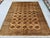 This warm Turkmen Bokhara rug features a dense grid of small octagonal medallions, each finely detailed with a stylized...