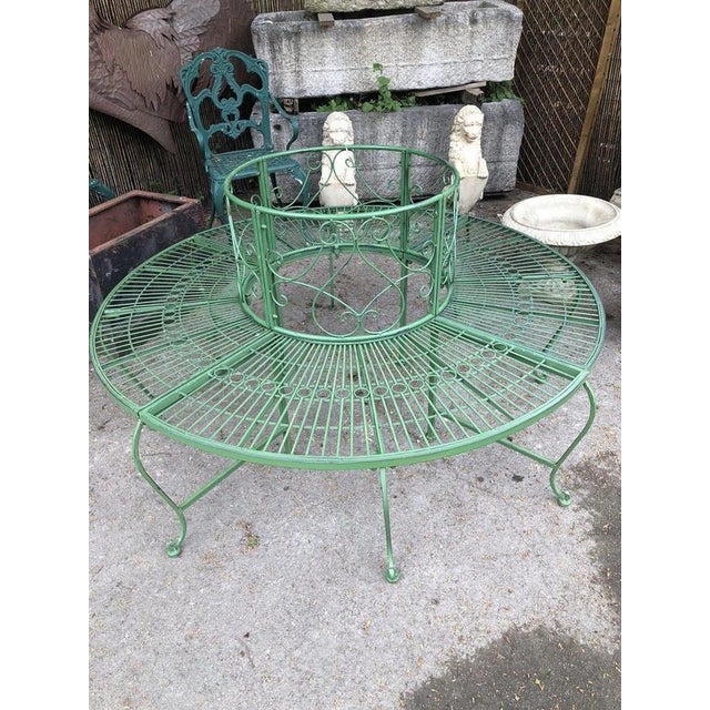 A charming circular metal tree bench in the French garden style, designed to surround the trunk of a tree and create an...