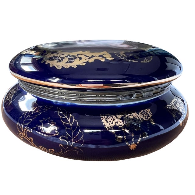 A beautiful cobalt blue trinket box with a hinged lid. The top features a scene of the Madonna and Child, with a wreath of...