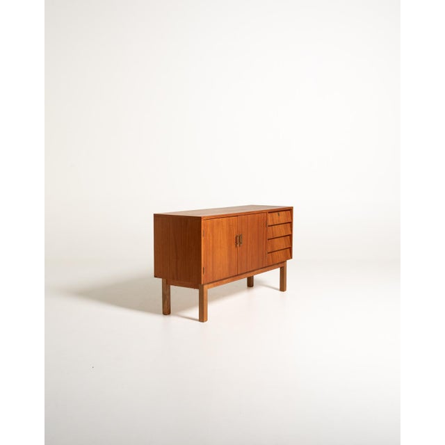 Mid-twentieth-century Scandinavian teak sideboard with two doors, four slanted drawers, and a base with square legs. Mid-...