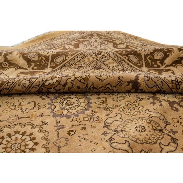 Beautiful antique Tabriz hand-knotted wool rug with a light brown field. This Persian piece has green, brown, and beige...