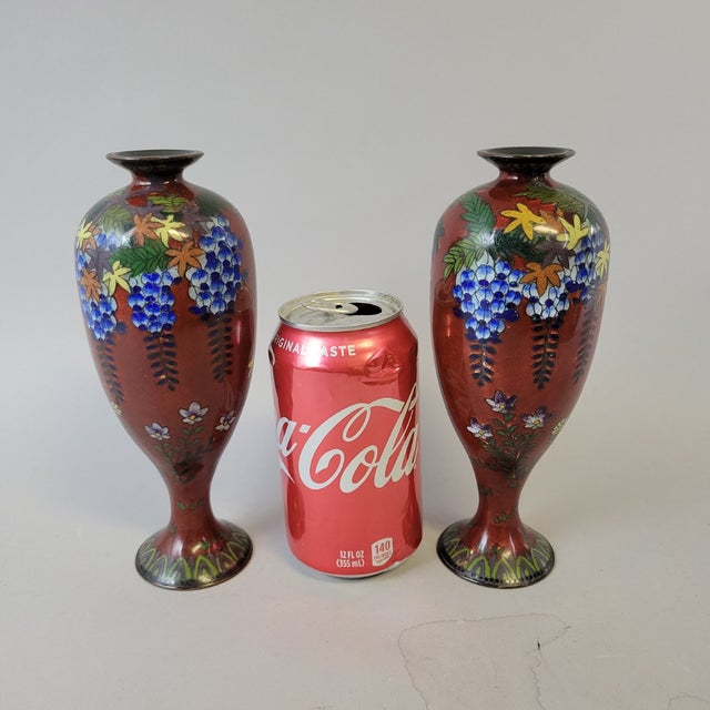 A vibrant pair of Japanese ginbari cloisonné vases, each showcasing a luminous translucent warm rust/red enamel applied...