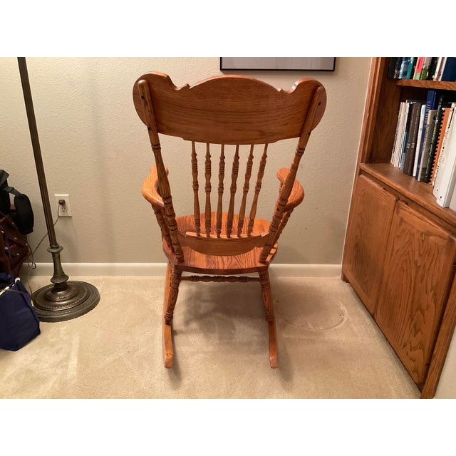 A solid oak rocking chair with pressed design on the front. This chair was purchased 38 years ago from specialty Oak...