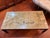 A large, Asian style mid 20th century coffee table, with a mountain landscape simply rendered on a sage, gray- green top....