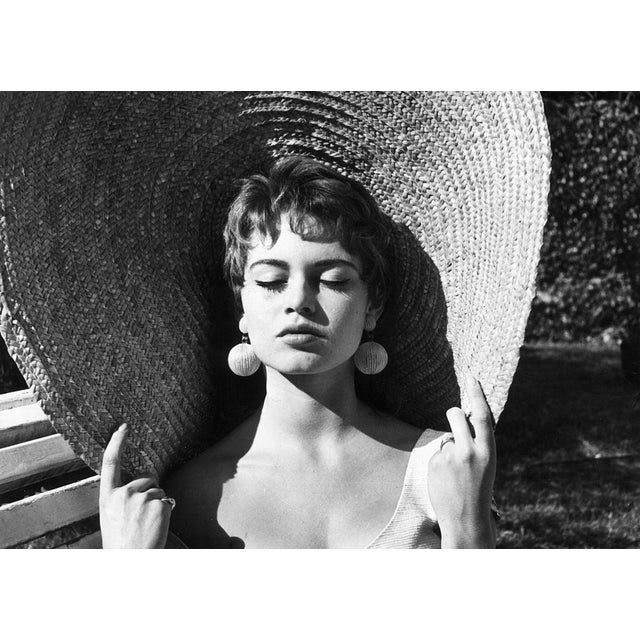 Brigitte Bardot circa 1955: Headshot of French actor Brigitte Bardot closing her eyes and holding the rim of her straw hat...