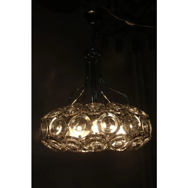 This 1970s chandelier features a chromed metal structure and thick glass lenses. Up to 250V (Europe/UK Standard).The...