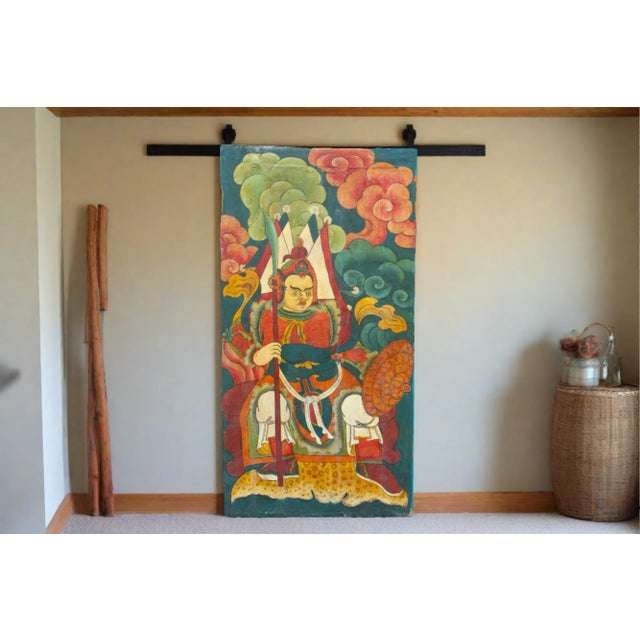 This bright Tibetan door from the 19th century features a painted leather front depicting a landscape scene with a...