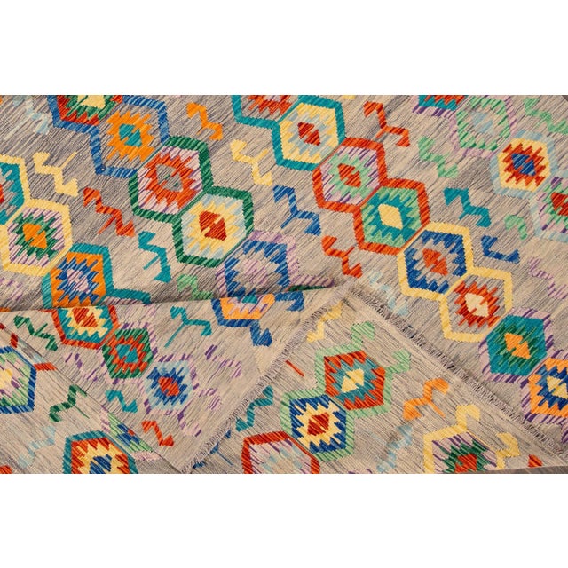 Beautiful Modern Kilim hand-knotted Wool Rug with an all over geometric design on a gray field. This Klim rug has multi-...