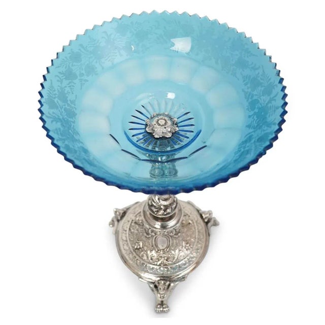 A silver Victorian plated compote dish with floral etched blue crystal mounted dish. Supported by a nude figure and...