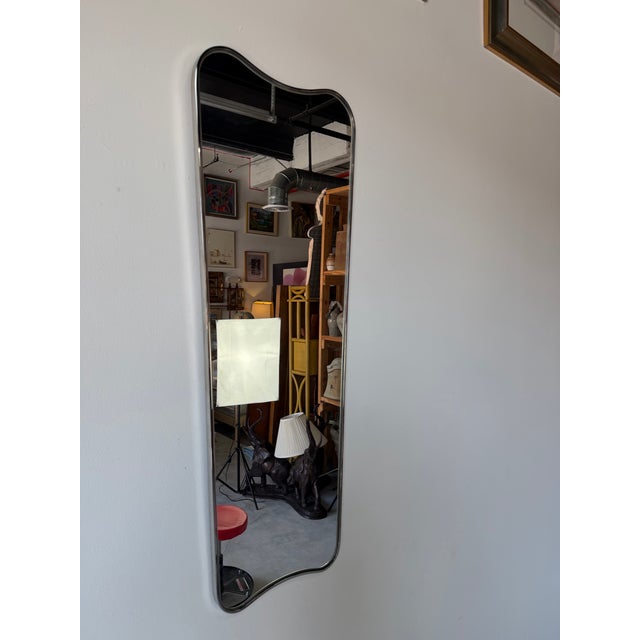 Striking vintage wall mirror featuring a sleek stainless steel and chrome frame with an elegant organic silhouette. The...