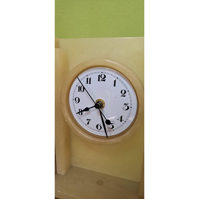 Art Deco architectural style mantel clock, handcrafted from amber-toned alabaster, with a distinctive stepped structure on...