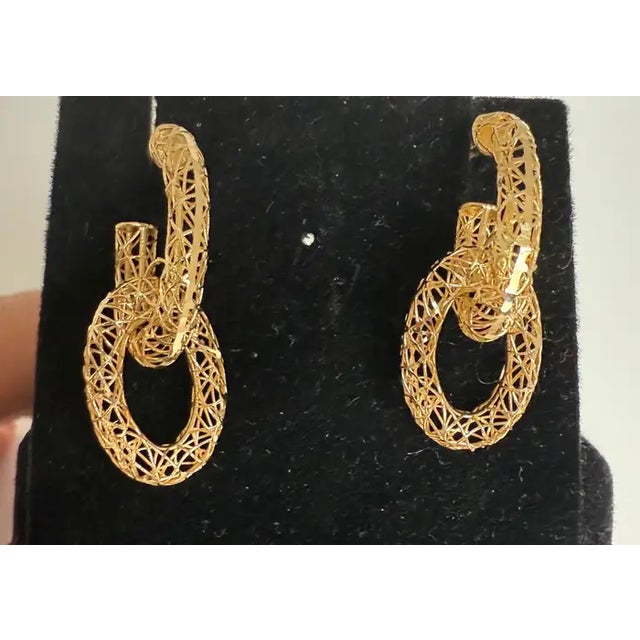 Elegant and ethereal, these 18K gold dangle earrings feature a refined filigree design reminiscent of the timeless...