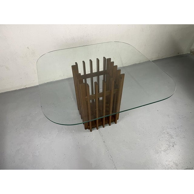 Sculptural table with finely crafted wooden base and glass top, of Italian manufacture from the 1970s. The table has been...