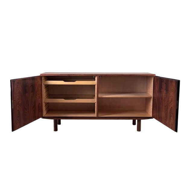 The stunning rosewood grain detail enhances the rich wood patina of this vintage storage piece. Masterfully crafted in...